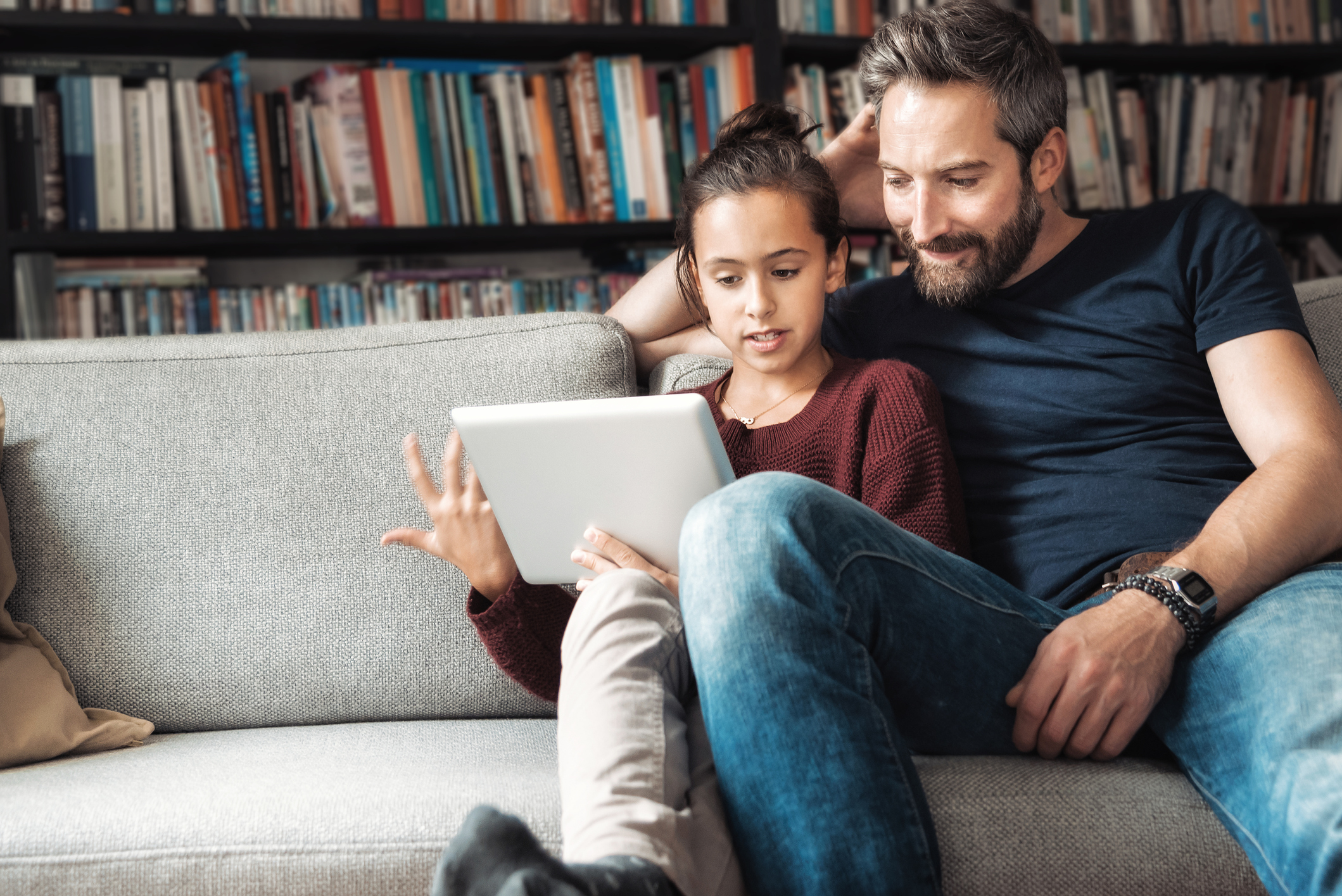 happy father and daughter having fun with digital tablet on couch